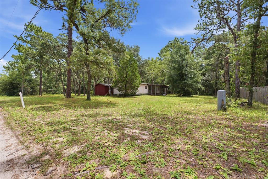 A mobile home with a screened porch sits on a grassy lot among many trees — 1821 N SHIREY POINT, INVERNESS, FL