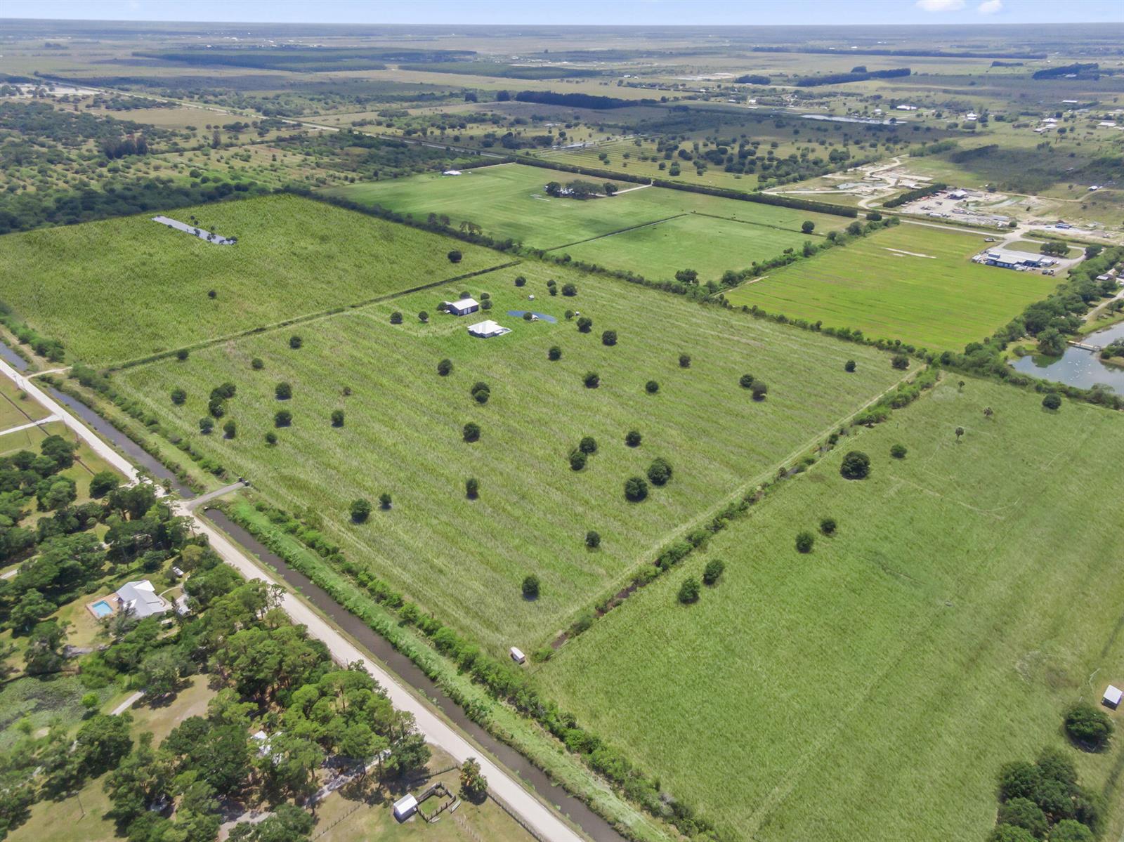 An aerial view shows a large, grassy rural property with a house, outbuildings, and trees — 1545 Pulitzer Road, Fort Pierce FL 34945, FORT PIERCE, FL