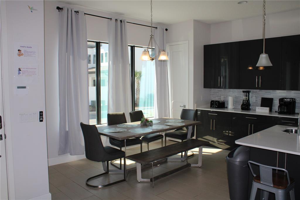 A dining area with a wooden table, chairs, a bench, and dark kitchen cabinets — 108 VILLA DOMANI CIRCLE, DAVENPORT, FL