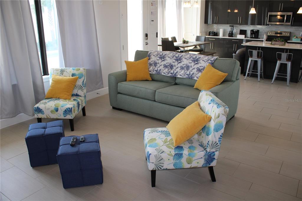A living room features a green sofa, two patterned armchairs, and two blue ottomans — 108 VILLA DOMANI CIRCLE, DAVENPORT, FL