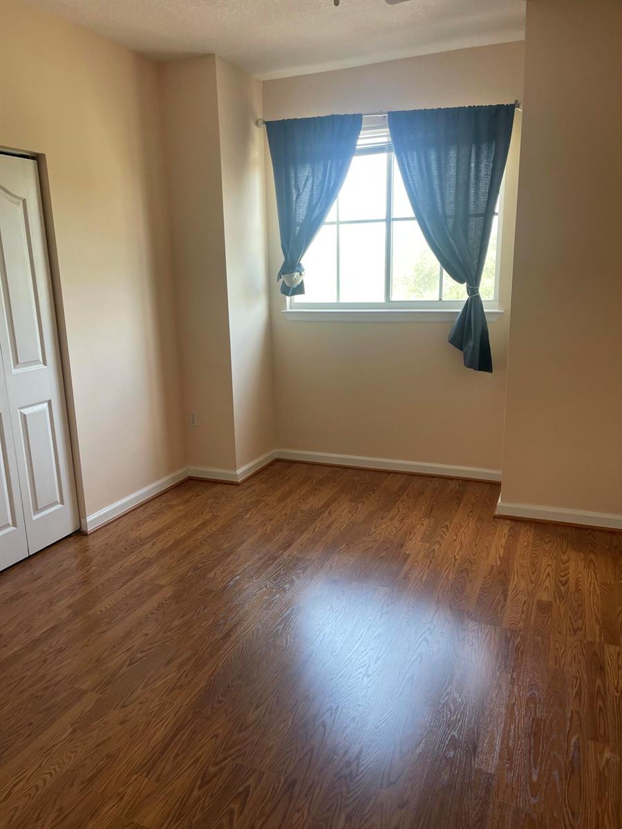 An empty bedroom features light-colored walls, wood-look flooring, and a window with dark curtains — 2040 Alta Meadows Lane # 1605, Delray Beach FL 33444, DELRAY BEACH, FL