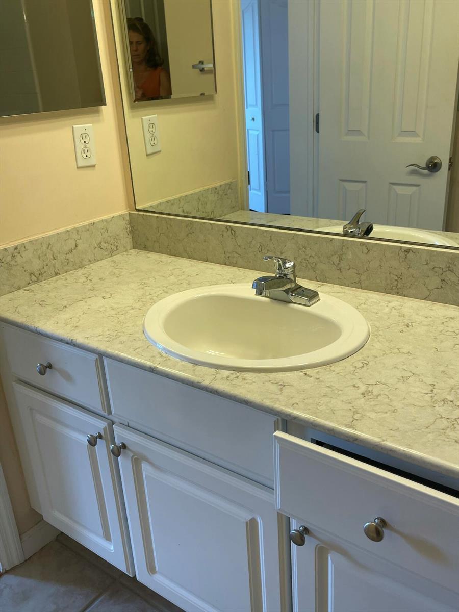 A bathroom vanity features a white sink, light-colored stone countertop, and white cabinets — 2040 Alta Meadows Lane # 1605, Delray Beach FL 33444, DELRAY BEACH, FL