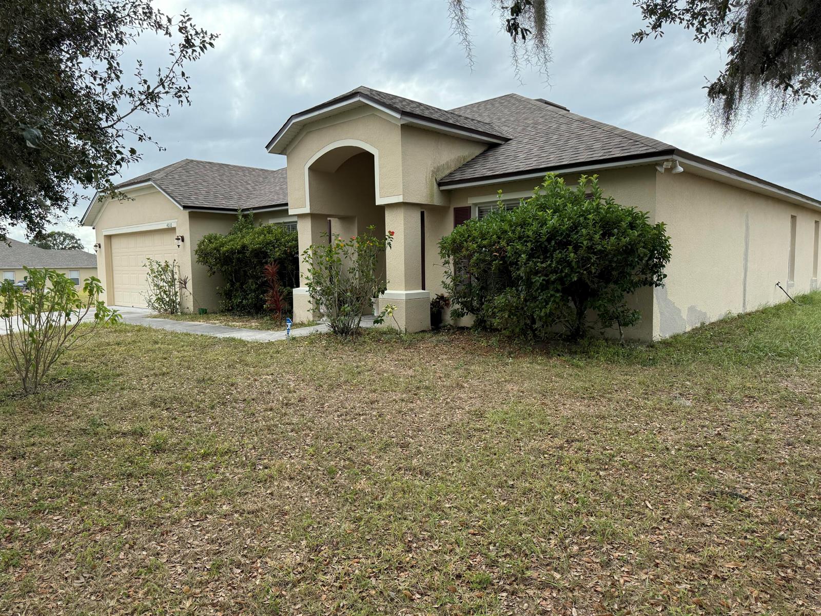 A single-story beige stucco house with a two-car garage and a covered entryway — 4010 Watkins Road, FL 33844, FL