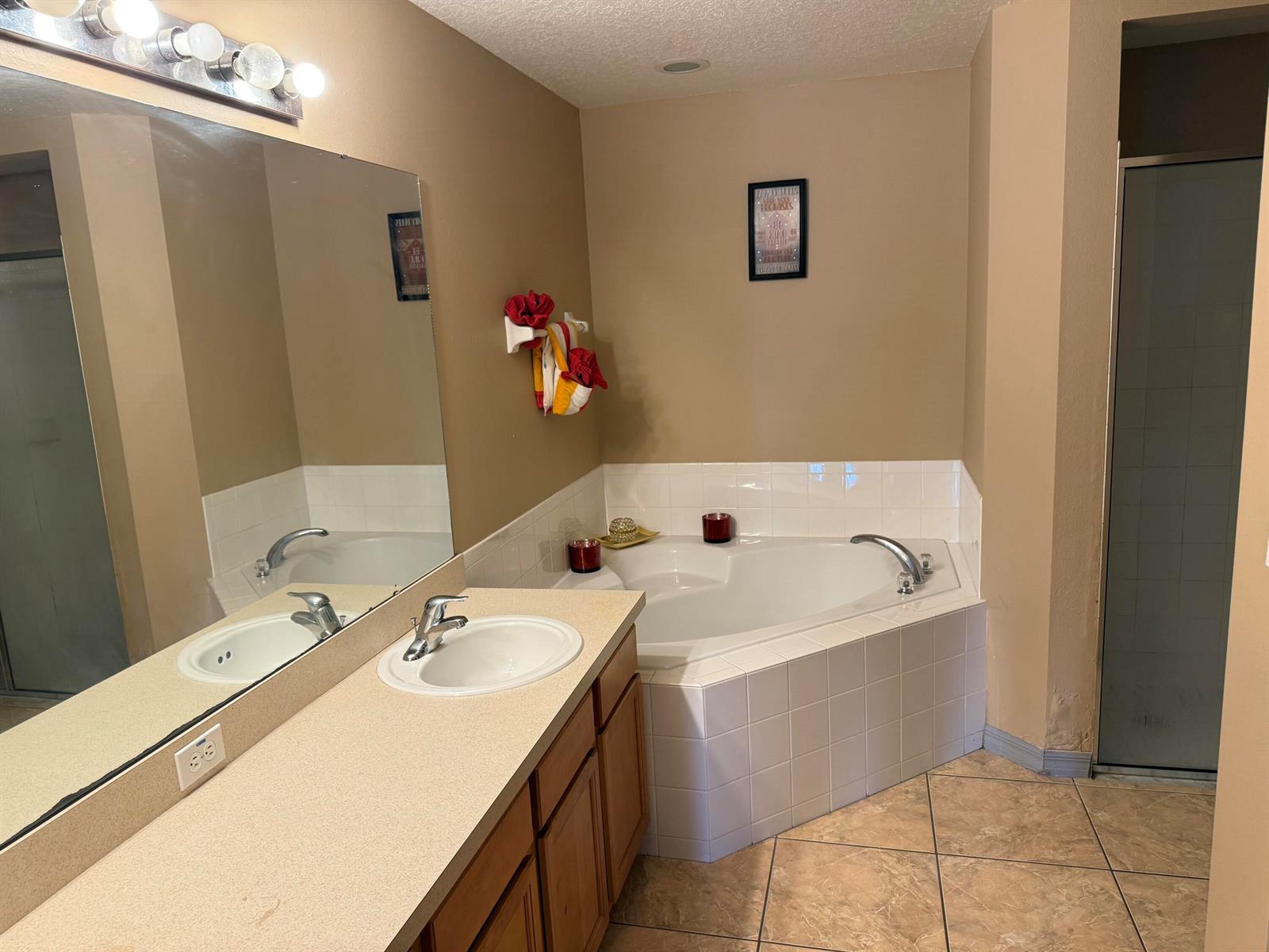 A bathroom features a corner soaking tub, a single vanity with a mirror, and tile flooring — 4010 Watkins Road, FL 33844, FL