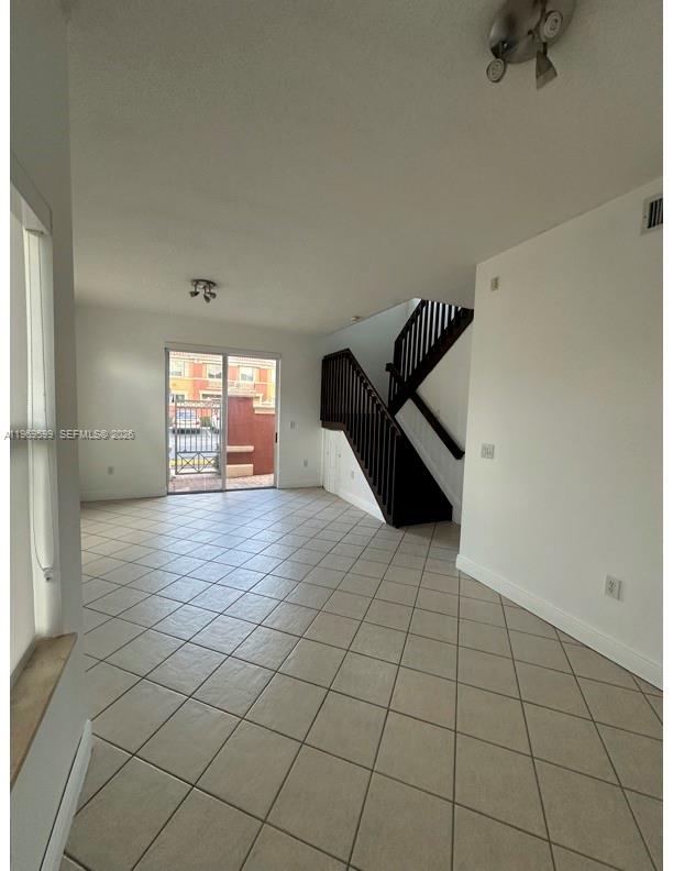 An interior view of a living area featuring tile flooring, a staircase, and sliding doors — 11438 NW 62nd Ter # 226, Doral FL 33178, DORAL, FL