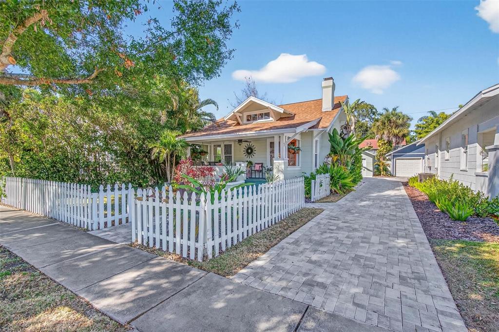A light green bungalow with a white picket fence and a paved driveway — 227 11TH AVENUE NE, ST PETERSBURG, FL