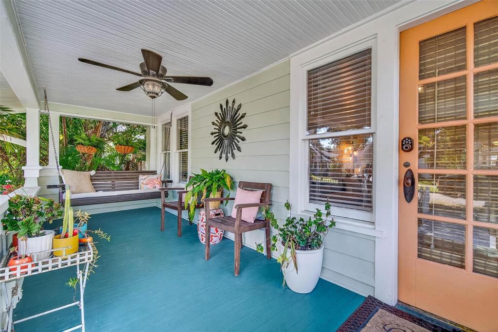 A covered front porch features a teal painted floor, a hanging swing, and wooden chairs — 227 11TH AVENUE NE, ST PETERSBURG, FL