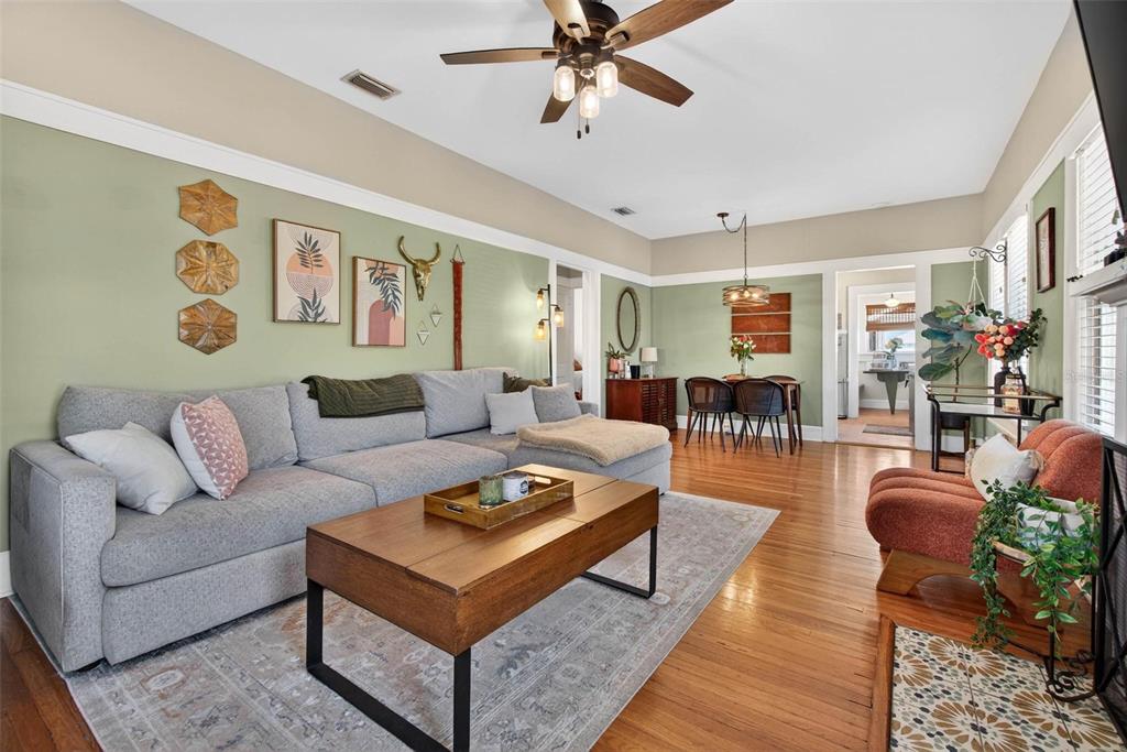 A living room with sage green walls, a gray sectional sofa, and hardwood floors — 227 11TH AVENUE NE, ST PETERSBURG, FL