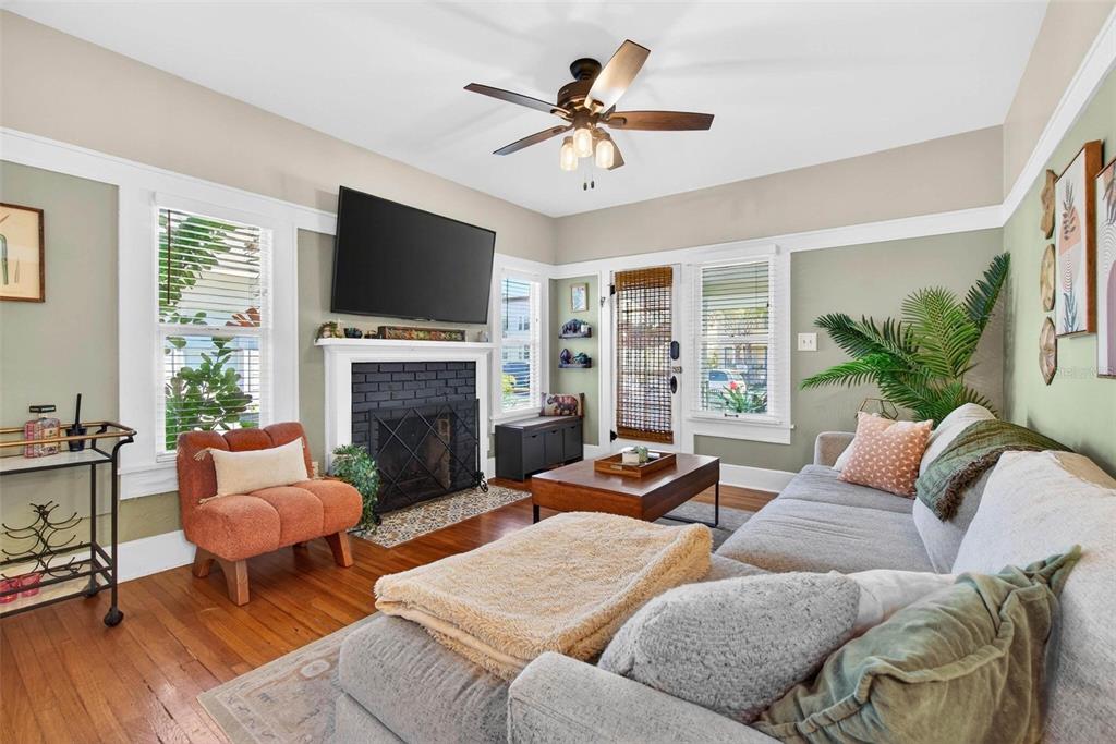 A living room features a black brick fireplace, a ceiling fan, and hardwood floors — 227 11TH AVENUE NE, ST PETERSBURG, FL