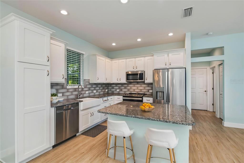 A kitchen features white cabinets, granite countertops, stainless steel appliances, and a central island — 9453 SINGER CIRCLE, PORT CHARLOTTE, FL