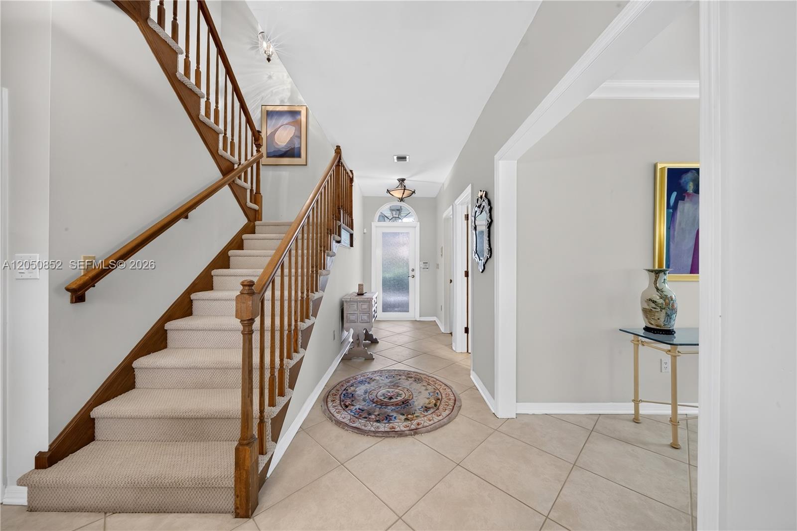 An entryway features a carpeted staircase with wooden railings, tile flooring, and a front door — 4820 Campo Sano Ct, Coral Gables FL 33146, CORAL GABLES, FL