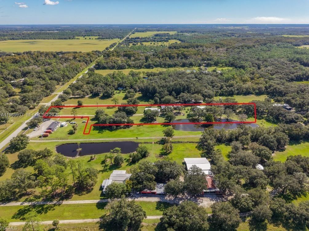An aerial view shows a rural property with multiple buildings, ponds, and trees — 0 Loblolly Bay Rd, FL 33935, FL