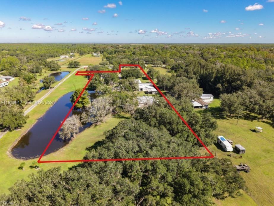 An aerial view shows a rural property with a house, trees, and a pond — 0 Loblolly Bay Rd, FL 33935, FL