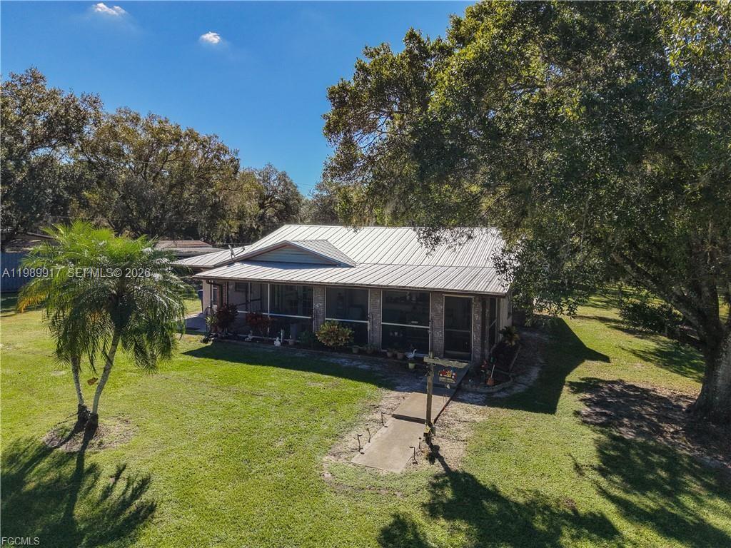 A single-story house with a metal roof and a screened-in porch sits on a lawn — 0 Loblolly Bay Rd, FL 33935, FL