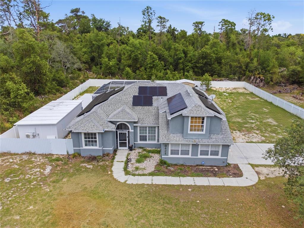 An aerial view of a gray house with solar panels and a white fence — 8424 BALM STREET, WEEKI WACHEE, FL
