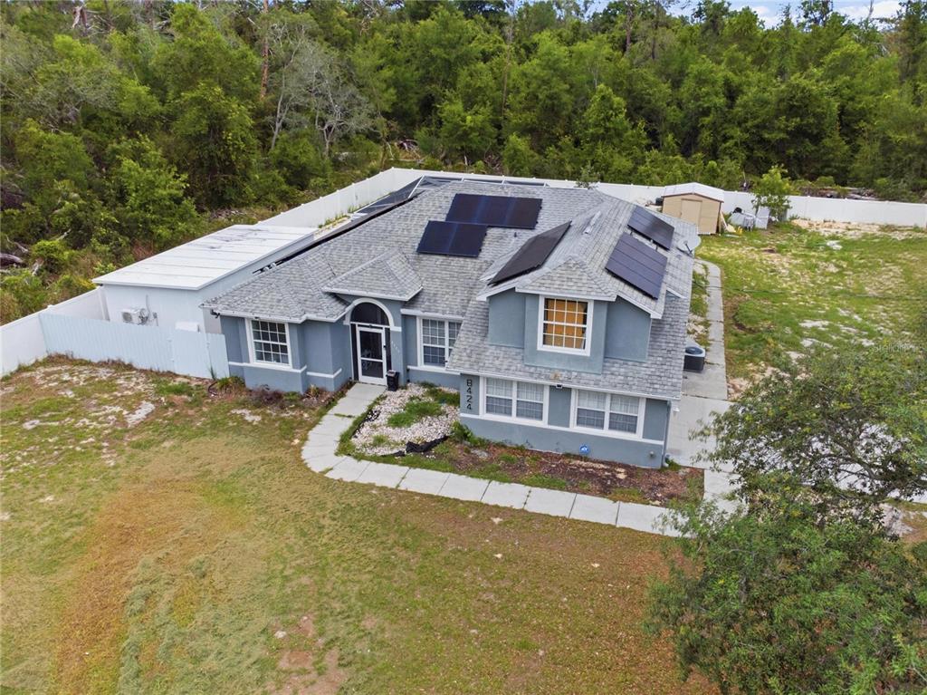 An aerial view of a gray house with solar panels on the roof and a yard — 8424 BALM STREET, WEEKI WACHEE, FL