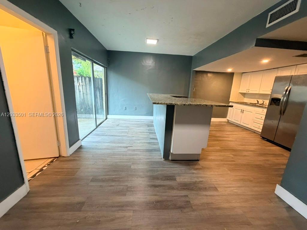 A kitchen with white cabinets and a granite-topped island opens to a living area — 274 NE 141st St # 3C, Miami FL 33161, MIAMI, FL
