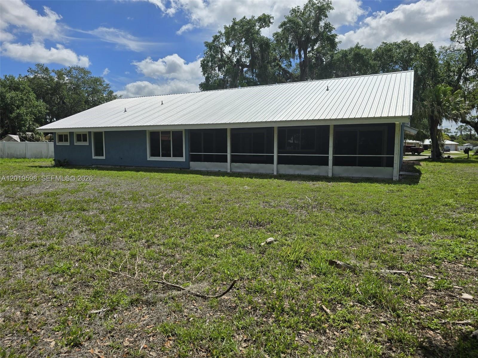A blue house with a white metal roof and a screened-in back porch — LA BELLE, FL