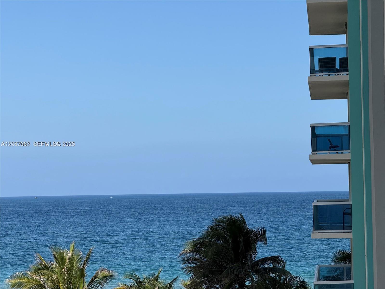 A view of the ocean and palm trees from a building with stacked balconies — 9201 Collins Ave # 521, Surfside FL 33154, SURFSIDE, FL