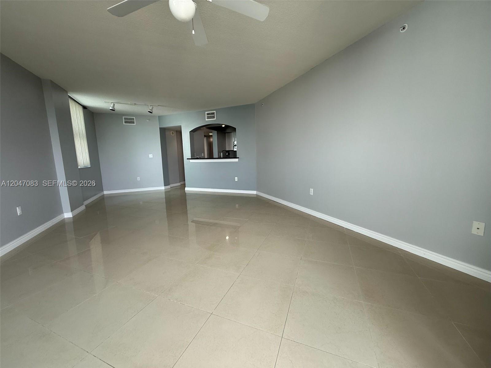 An empty living area features light gray walls, large beige floor tiles, and a ceiling fan — 9201 Collins Ave # 521, Surfside FL 33154, SURFSIDE, FL