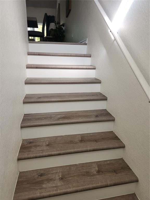 A staircase with wood-look treads and white risers leads to an upper landing — 6503 FAIRWAY GARDENS DRIVE, BRADENTON, FL