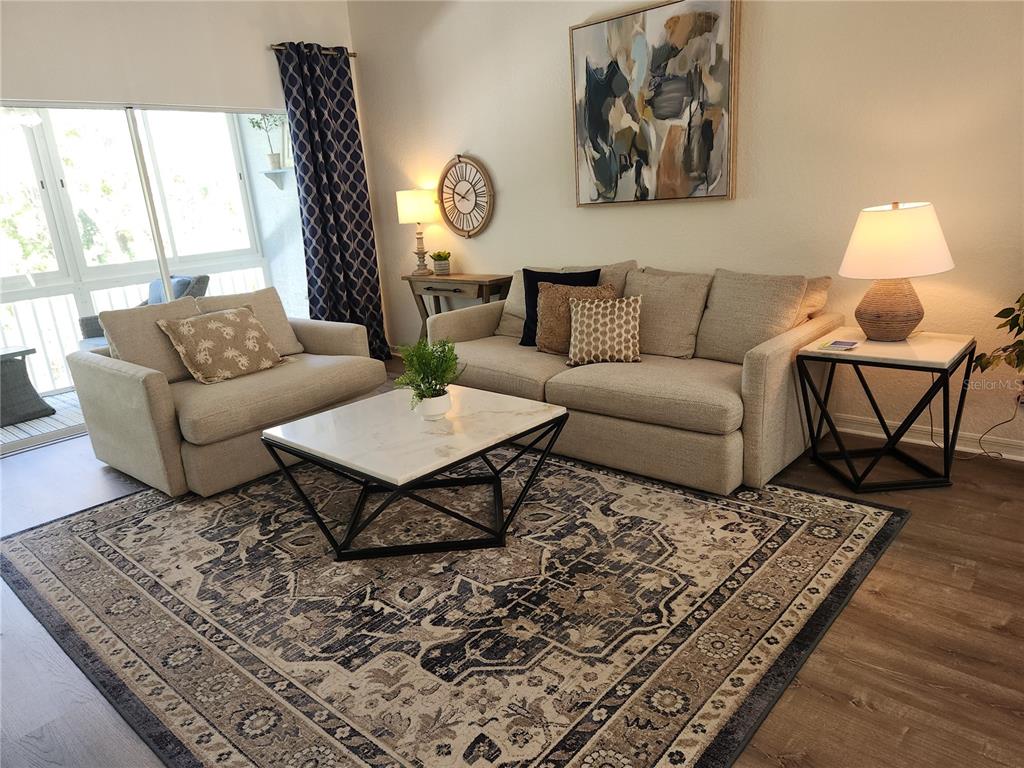 A living room features a beige sofa and armchair, a patterned rug, and a coffee table — 6503 FAIRWAY GARDENS DRIVE, BRADENTON, FL