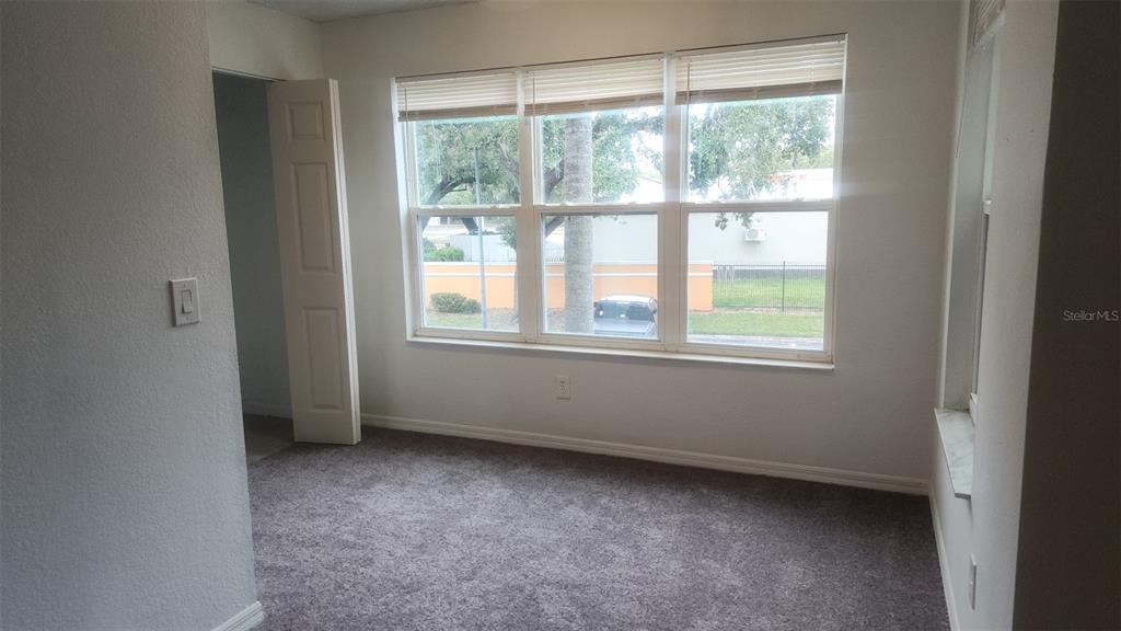 A bedroom with gray carpet, white walls, and a large window overlooking a parking lot — 4540 COMMANDER DRIVE UNIT 2224, ORLANDO, FL