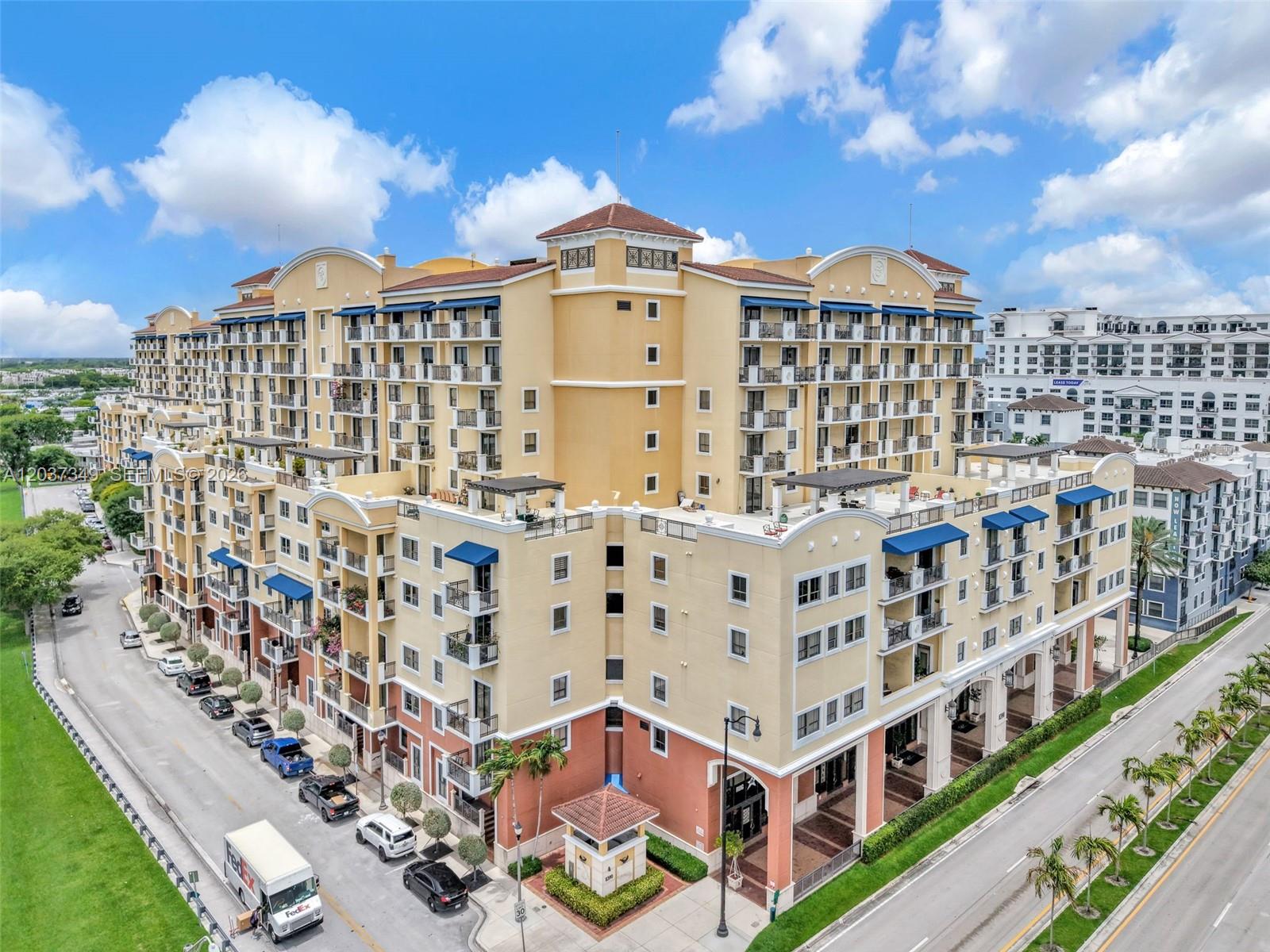 An aerial view shows a large, multi-story yellow apartment complex with balconies and ground-level retail — 8390 SW 72nd Ave # 905, Miami FL 33143, MIAMI, FL