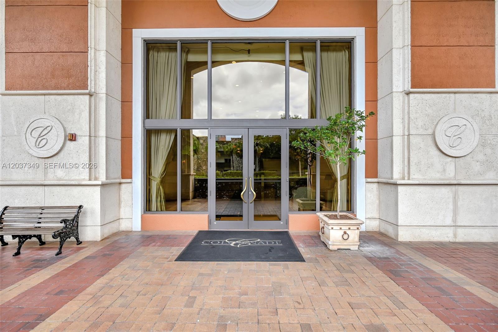 The entrance to a building features a glass double door, a bench, and a planter — 8390 SW 72nd Ave # 905, Miami FL 33143, MIAMI, FL