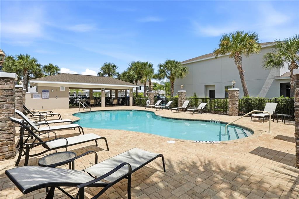 An outdoor swimming pool with lounge chairs on a paved deck near a covered pavilion — 6453 BAYTOWN DRIVE, SARASOTA, FL