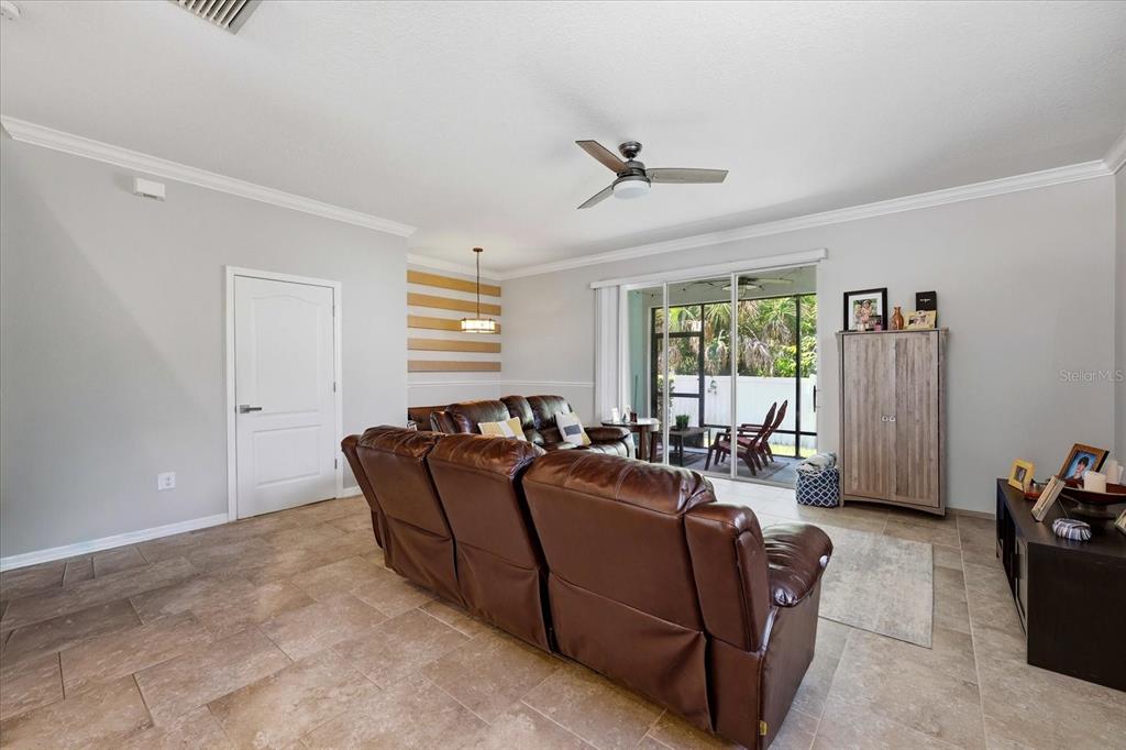 A living room features brown leather reclining sofas, tile flooring, and a sliding glass door — 6453 BAYTOWN DRIVE, SARASOTA, FL