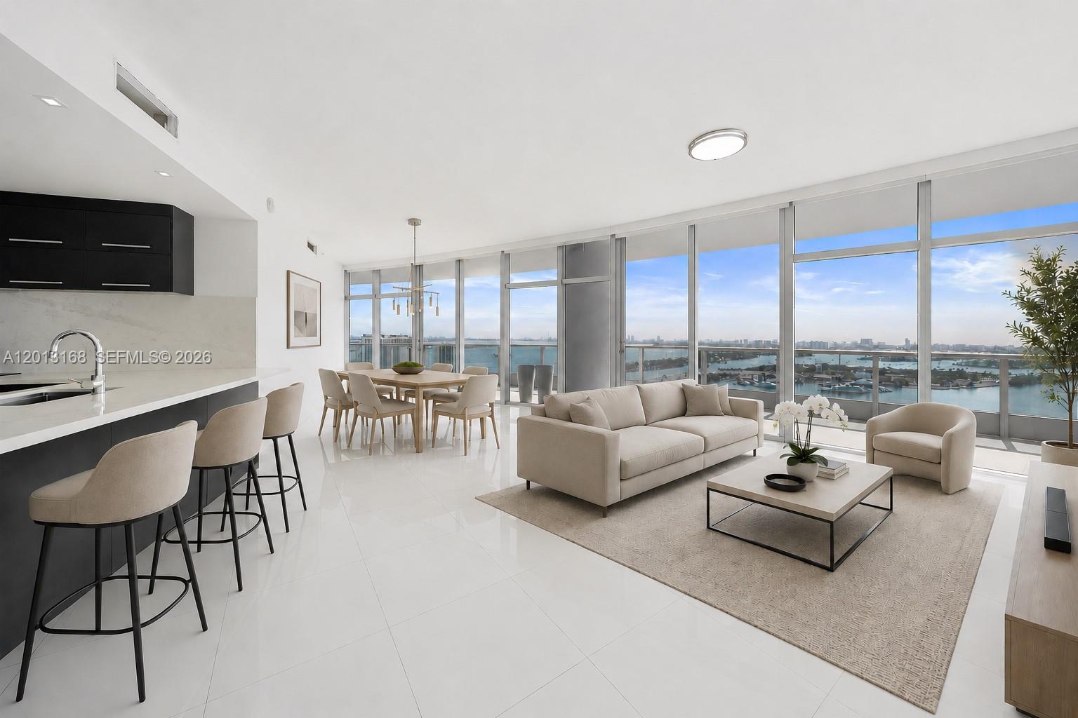 A modern kitchen with dark cabinetry and white tile floors overlooks a balcony and water — 900 Biscayne Blvd # 4006, Miami FL 33132, MIAMI, FL