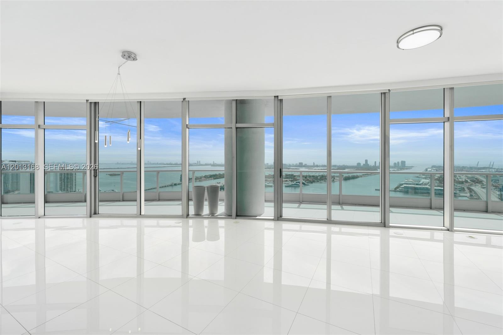 A bright, empty room with white tile floors and floor-to-ceiling windows overlooking the ocean — 900 Biscayne Blvd # 4006, Miami FL 33132, MIAMI, FL