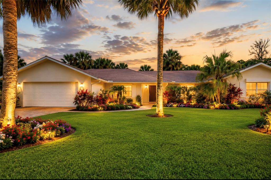 A single-story house with a white garage, palm trees, and landscaped yard at sunset — 55 BAY HARBOUR DRIVE, PONCE INLET, FL