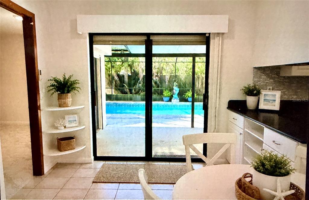 A dining area features a sliding glass door looking out to a backyard swimming pool — 55 BAY HARBOUR DRIVE, PONCE INLET, FL