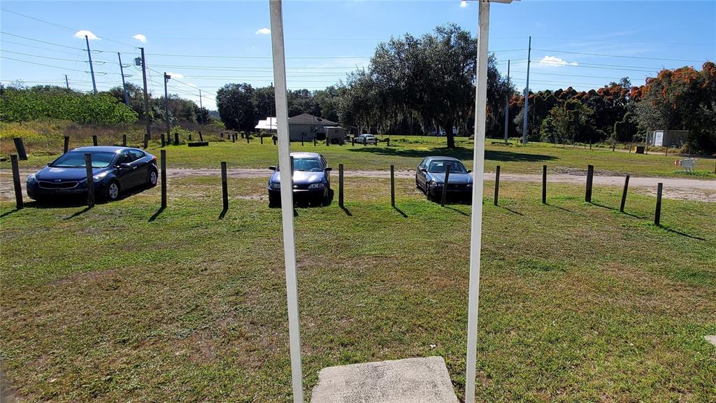 A grassy lot features three parked cars and a fence line under a clear sky — 1002 DANIELS STREET, DUNDEE, FL