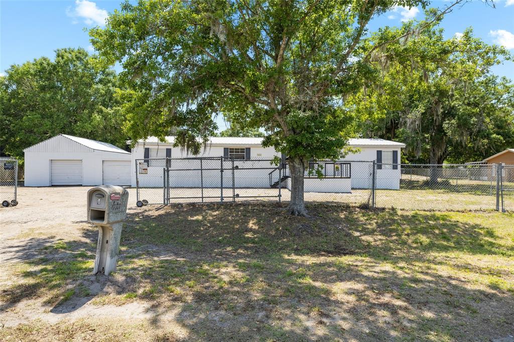 A white single-story house with a detached garage and chain-link fencing in the front yard — 12507 ICEWOOD COURT, RIVERVIEW, FL