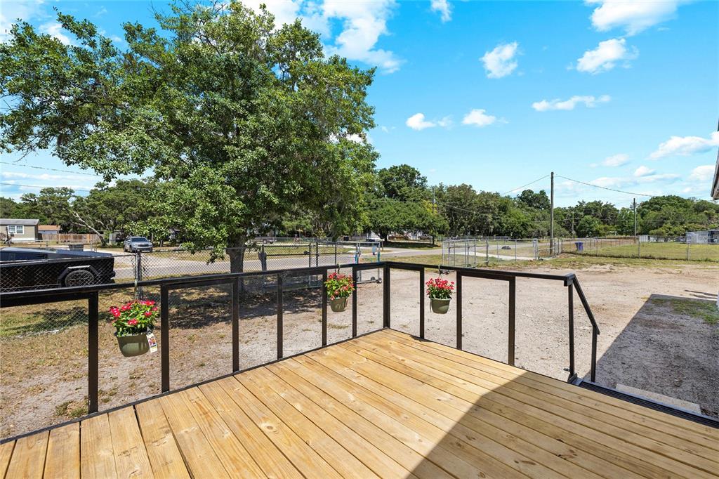 A wooden deck with a black metal railing overlooks a dirt yard and large tree — 12507 ICEWOOD COURT, RIVERVIEW, FL