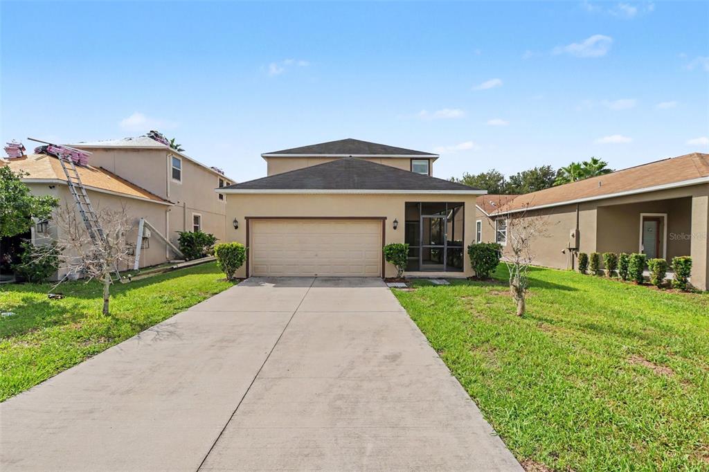 A two-story house with a beige stucco exterior, a two-car garage, and a screened porch — 21087 PLEASANT PLAINS PARKWAY, LAND O LAKES, FL