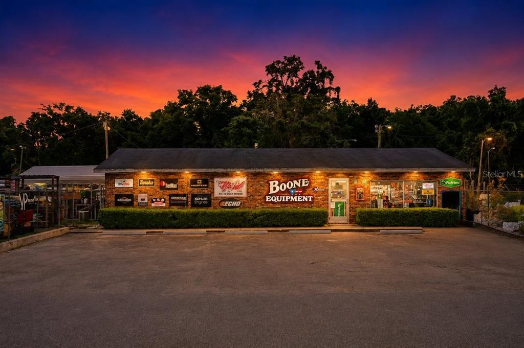 A brick commercial building with equipment brand signage stands under a vibrant sunset sky — 17962 NW US HIGHWAY 441, HIGH SPRINGS, FL