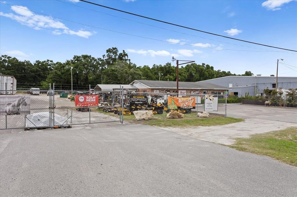 An outdoor view of a fenced equipment lot with several mowers and a commercial building — 17962 NW US HIGHWAY 441, HIGH SPRINGS, FL