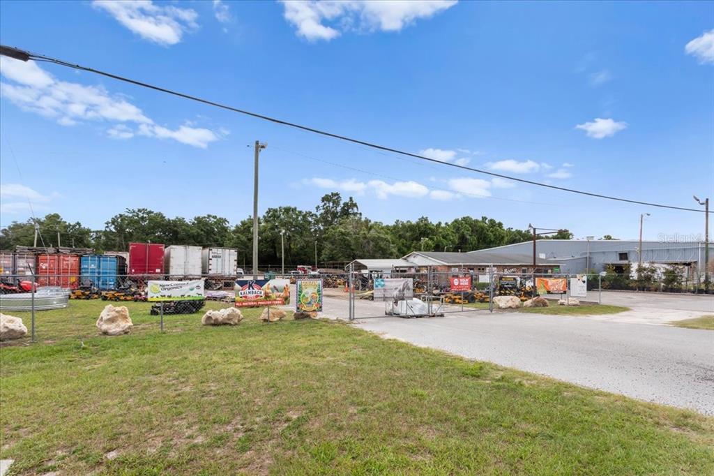 An outdoor view of a fenced commercial property with shipping containers and a warehouse building — 17962 NW US HIGHWAY 441, HIGH SPRINGS, FL