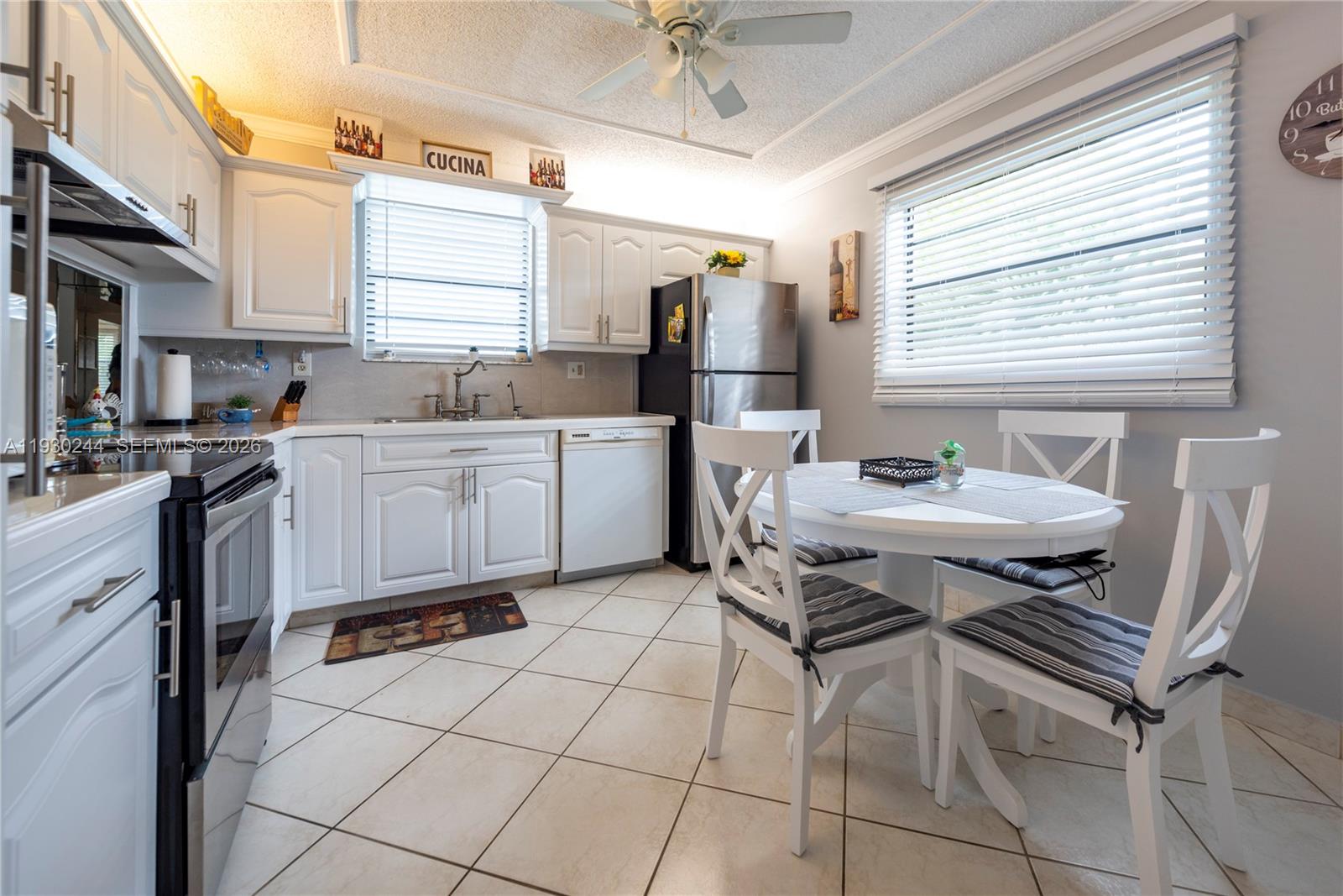 A dining area with a glass table and wooden chairs sits adjacent to a living room — 4940 E Sabal Palm Blvd # 414, Tamarac FL 33319, TAMARAC, FL