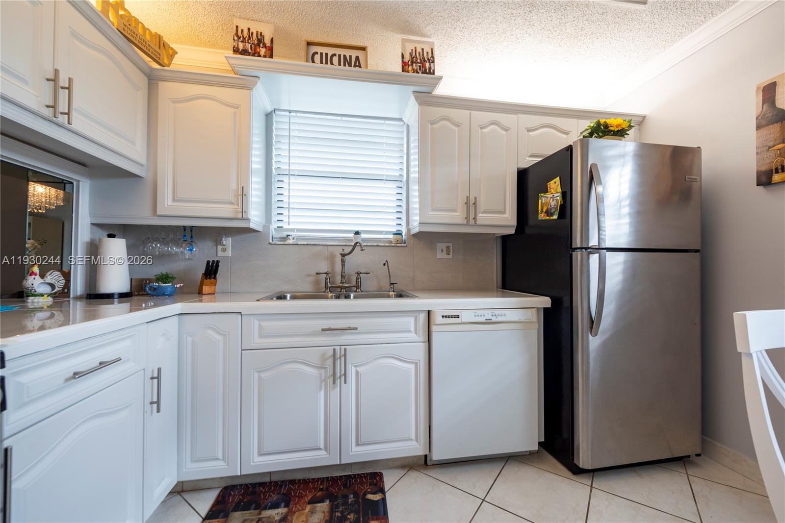 A kitchen features white cabinets, stainless steel appliances, a sink, and tiled flooring — 4940 E Sabal Palm Blvd # 414, Tamarac FL 33319, TAMARAC, FL