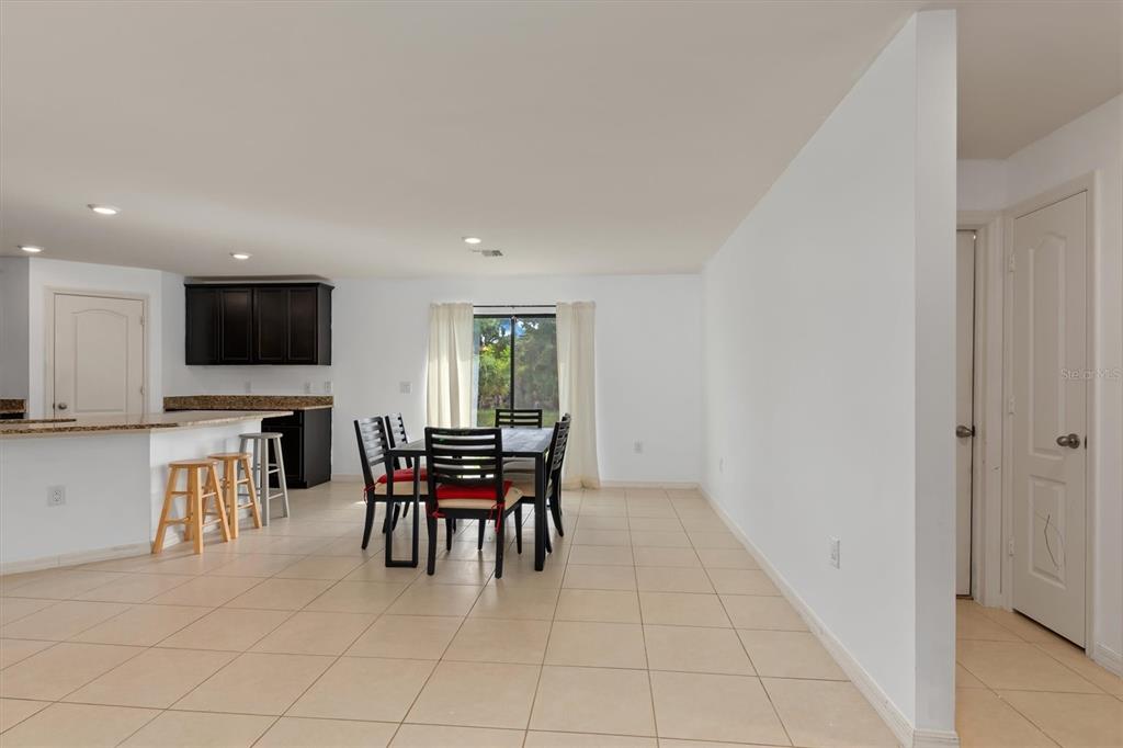 A dining area with a table and chairs sits adjacent to a kitchen with dark cabinets — 4234 GALVIN LANE, NORTH PORT, FL