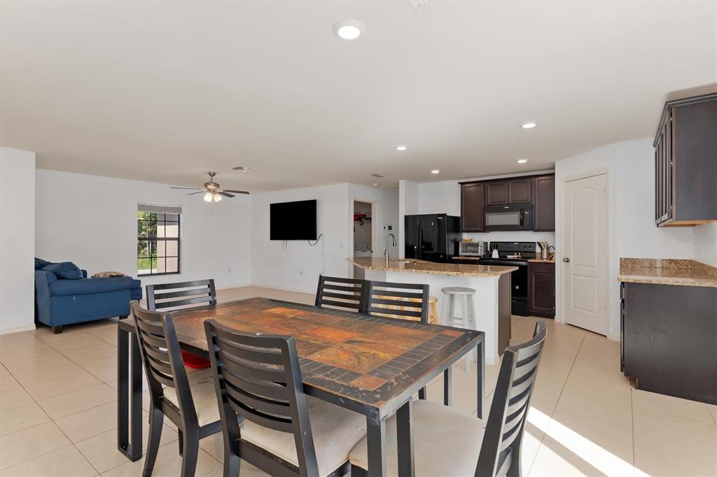 An open-concept dining area and kitchen feature dark wood cabinets, granite countertops, and tile flooring — 4234 GALVIN LANE, NORTH PORT, FL
