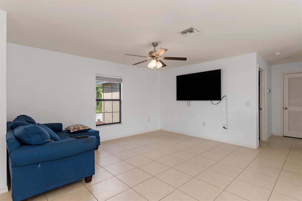 A living room features light blue walls, tile flooring, a ceiling fan, and a wall-mounted television — 4234 GALVIN LANE, NORTH PORT, FL