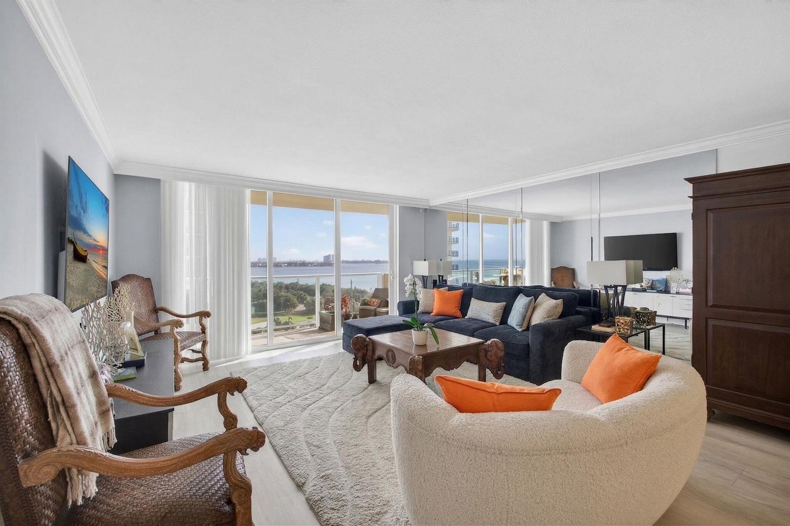 A living room features a dark sectional, a textured rug, and a balcony with water views — 5440 N Ocean Drive # 805, Singer Island FL 33404, SINGER ISLAND, FL