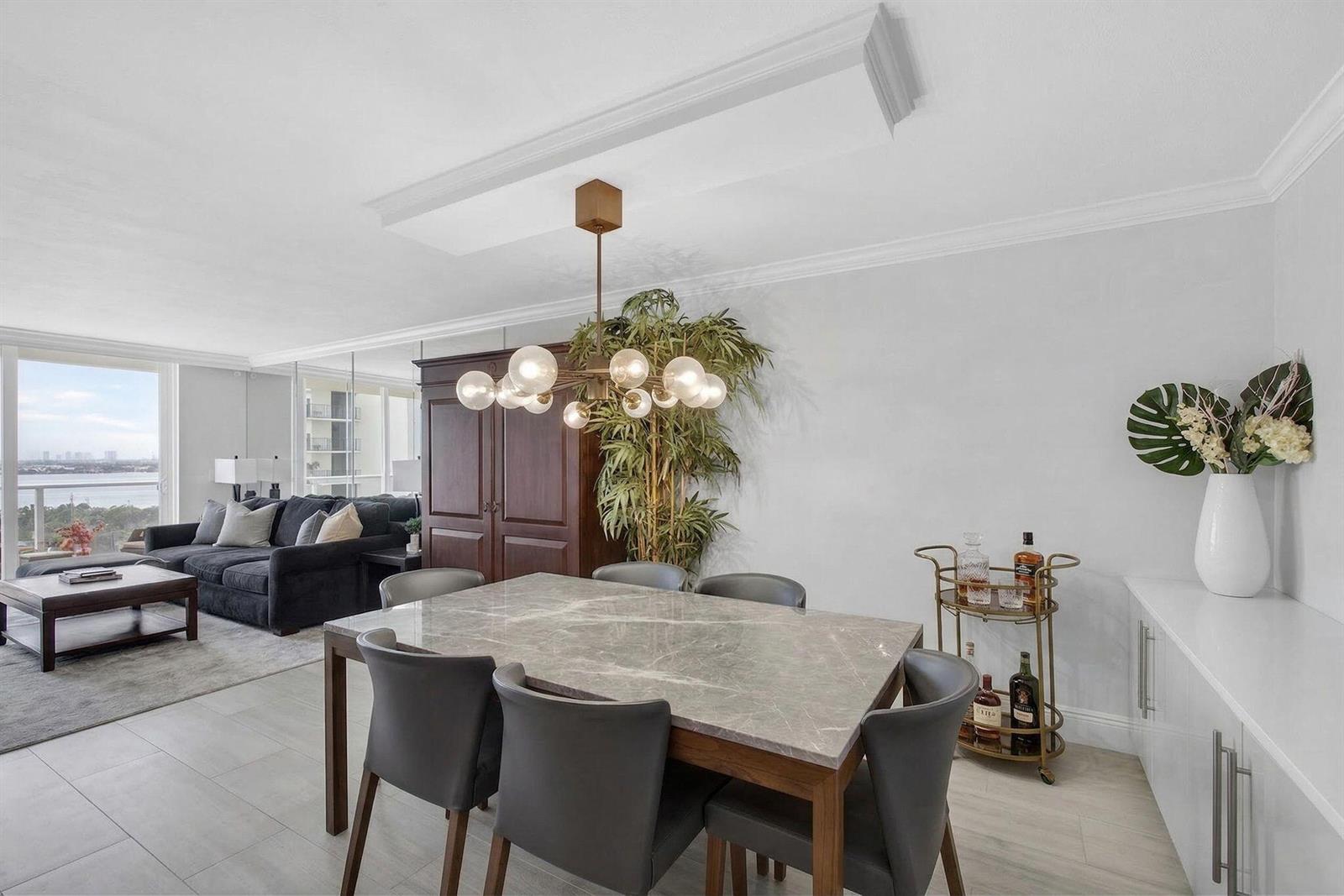 A dining area with a marble-top table, grey chairs, and a bar cart near a living room — 5440 N Ocean Drive # 805, Singer Island FL 33404, SINGER ISLAND, FL