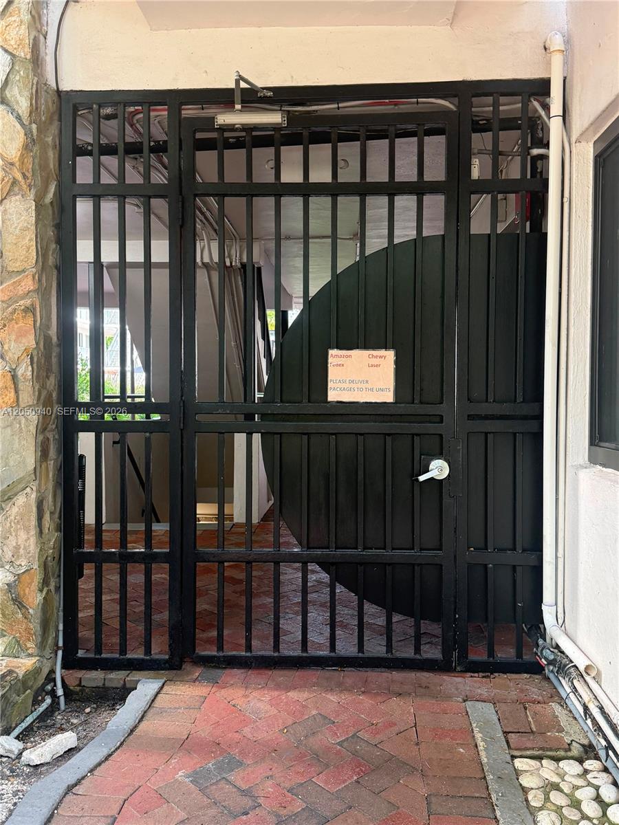 A black metal security gate stands at the entrance of a brick-paved walkway — 2924 Day Ave # N110, Miami FL 33133, MIAMI, FL